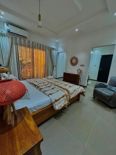 a bedroom with a large bed and a chair at Maisons d'Hotes Les jardins de keur fary 