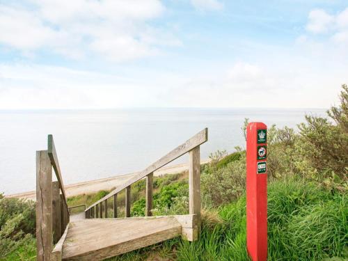 a wooden staircase to the beach with a red post at 4 person holiday home in Struer in Struer