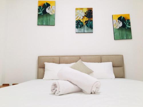 a white bed with four paintings on the wall at Diyon'S Lodge in Ella