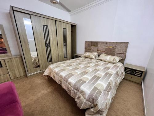 a bedroom with a large bed and a purple chair at الفاخر للشقق الفندقيه in Al Mafraq