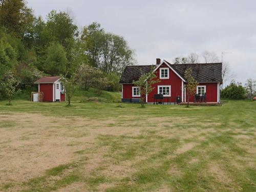 a red house in a field with a yard at 6 person holiday home in VESSIGEBRO in Vessigebro