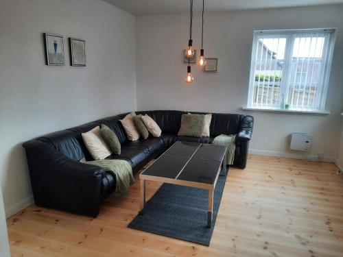 a black leather couch in a living room with a table at 7 person holiday home in Asnæs in Asnæs