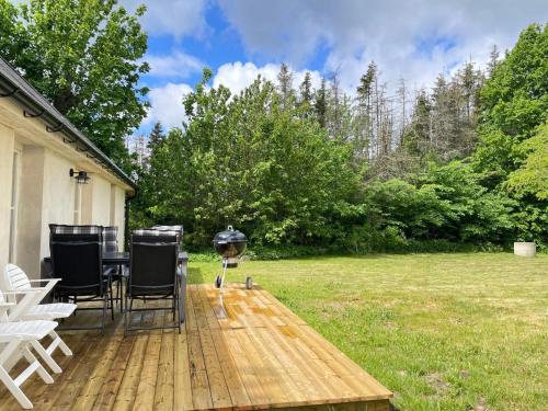 a grill on a wooden deck with chairs and a yard at 5 star holiday home in HAMMENHÖG in Hammenhög