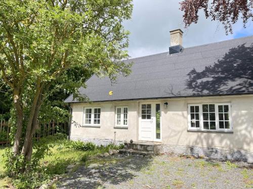 a white house with a tree in front of it at 5 star holiday home in HAMMENHÖG in Hammenhög