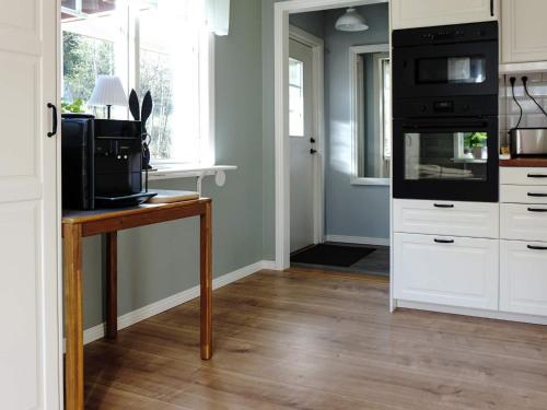 a kitchen with a table with a microwave and a stove at 4 star holiday home in TVÄRRED in Vasared