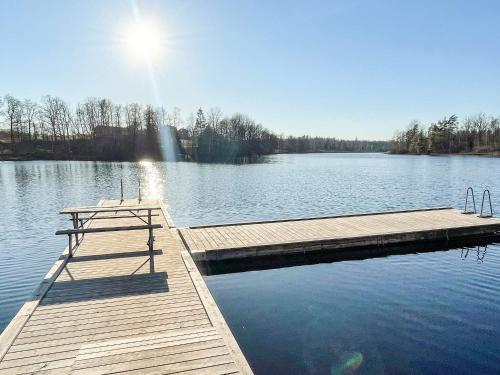 a dock on a lake with the sun shining on the water at 6 person holiday home in Kristdala in Kristdala