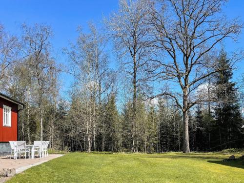 a yard with a red house and a table and chairs at 4 star holiday home in TVÄRRED in Vasared
