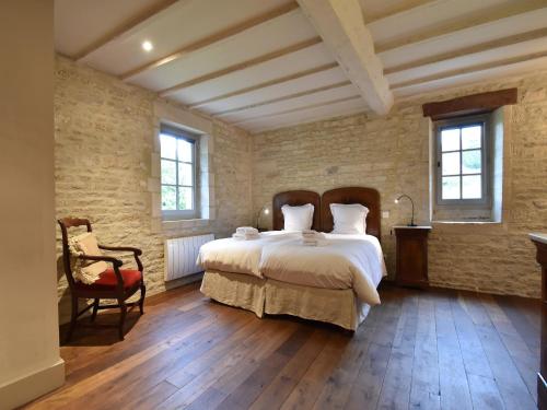 une chambre avec un grand lit blanc et une chaise dans l'établissement Manor in Normandy with Spa and Pool, cleaning included, à Lantheuil