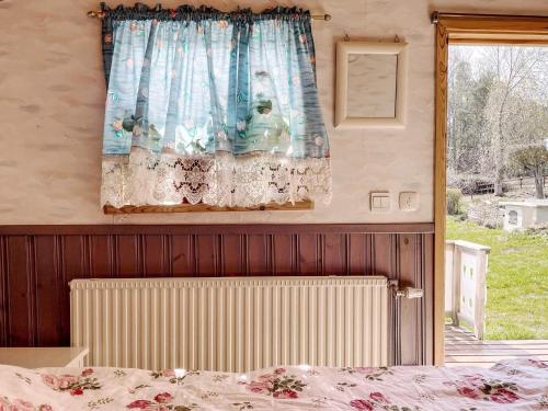 a bedroom with a bed and a window with a curtain at Charming Garden Cottage in Levide in Hemse