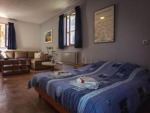 - une chambre avec un lit doté de draps bleus et d'un canapé dans l'établissement Cottage in Vézac with Pool and Barbecue, cleaning included, à Vézac