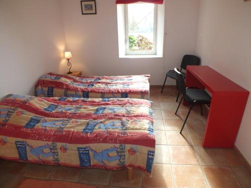 Habitación con 2 camas, escritorio y mesa roja. en Gîte - La Rigaudière, en Le Theil-de-Bretagne