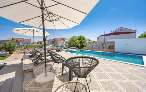 patio con sedie, ombrellone e piscina di Stunning Apartment In Vodice a Vodice