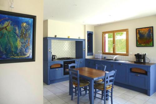 une cuisine avec des placards bleus et une table en bois dans l'établissement Stone House in Brittany near Scenic Bay, cleaning included, à Planguenoual