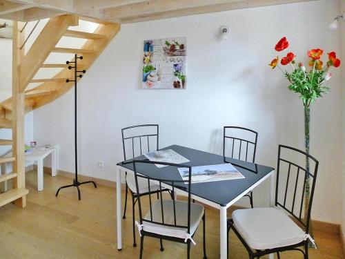 une salle à manger avec une table, des chaises et un vase de fleurs dans l'établissement Stone House in Plougasnou near Sandy Beach, cleaning included, à Plougasnou
