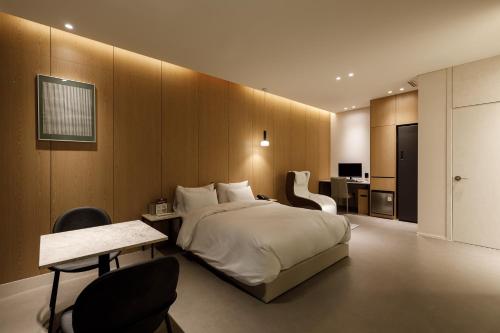 a bedroom with a large bed and a table and chairs at Just Sleep Hotel Suite Cheonan Station in Cheonan