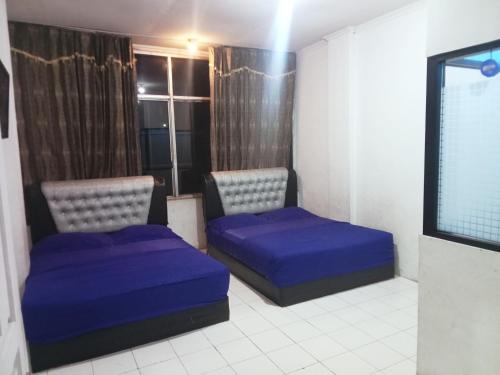 a room with two beds and a flat screen tv at Nafisha Hotel Bukittinggi in Bukittinggi