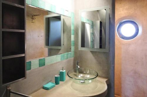 La salle de bains est pourvue d'un lavabo en verre et d'un miroir. dans l'établissement Stone House near Rosa Granite Coast, cleaning included, à Bas Kerhain