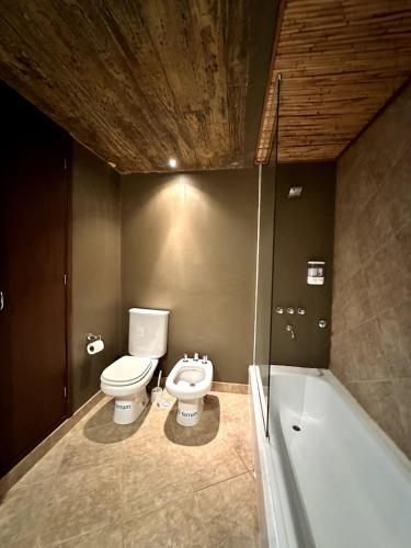 a bathroom with a toilet and a bath tub at Red Hill Lodge Purmamarca in Purmamarca