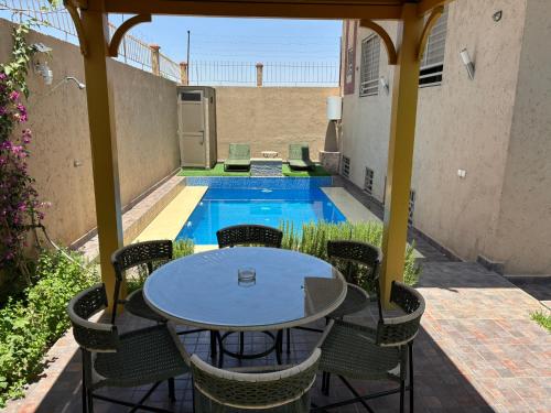 a patio with a table and chairs and a swimming pool at Villa-Appart Sara, superbe jardin & piscine privée in Marrakech