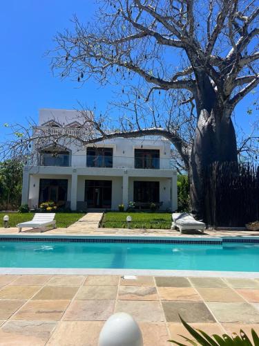 a large white house with a swimming pool and a tree at 3bed oceanfront with Ac &gazebo in Kwale