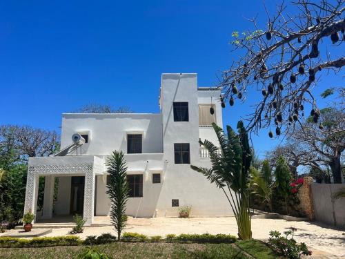 a large white house with a palm tree in front of it at 3bed oceanfront with Ac &gazebo in Kwale