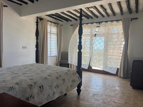 a bedroom with a canopy bed and a window at 3bed oceanfront with Ac &gazebo in Kwale
