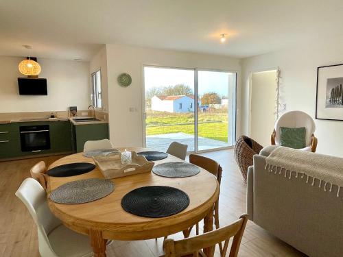 Il comprend un salon avec une table en bois et une cuisine. dans l'établissement Maison neuve 3 chambres, 6 couchages, entre mer et campagne, accès bourg à pied, WIFI - FR-1-231-329, à Bretignolles-sur-Mer