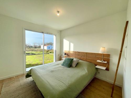 une chambre avec un grand lit avec une grande fenêtre dans l'établissement Maison neuve 3 chambres, 6 couchages, entre mer et campagne, accès bourg à pied, WIFI - FR-1-231-329, à Bretignolles-sur-Mer
