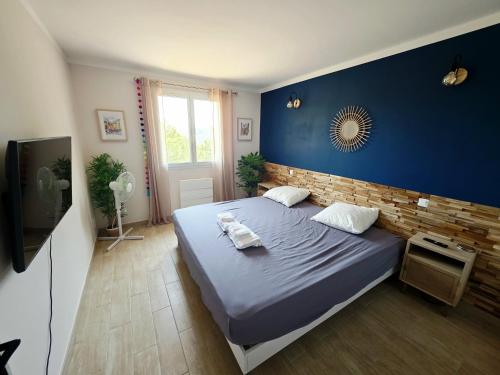 une chambre avec un grand lit avec un mur bleu dans l'établissement Casa Agave-Charmante maison avec étage offrant des prestations de qualité., à Sillans-la-Cascade