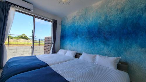 a bedroom with a large bed with a blue wall at Klasse Villa Miyako in Miyako-jima