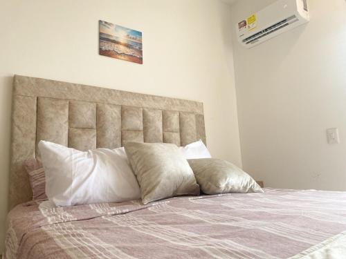 a bed with white pillows on top of it at Apartamento nuevo con vista al mar, Santa Marta in Santa Marta
