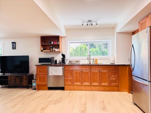 a kitchen with a stainless steel refrigerator and wooden cabinets at Peaceful 2-bedroom, 1-bath daylight suite with private entrance in West Kelowna