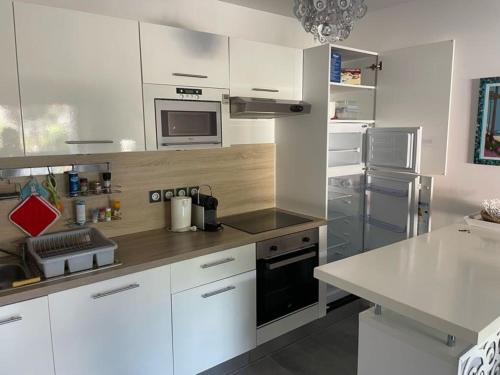 une cuisine avec des armoires blanches et des appareils en acier inoxydable dans l'établissement Appartement de standing avec jardin privatif, proche du lac et du centre, parking inclus - FR-1-239-583, à Soorts-Hossegor