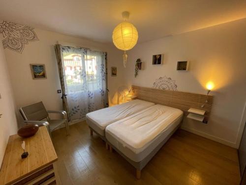 ein Schlafzimmer mit einem Bett, einem Tisch und einer Lampe in der Unterkunft Appartement de standing avec jardin privatif, proche du lac et du centre, parking inclus - FR-1-239-583 in Soorts-Hossegor