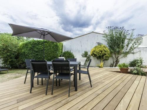 une table et des chaises avec un parasol sur une terrasse en bois dans l'établissement Maison de plain pied avec jardin clos pour 6 personnes - FR-1-835-26, à Sainte-Marie de Ré