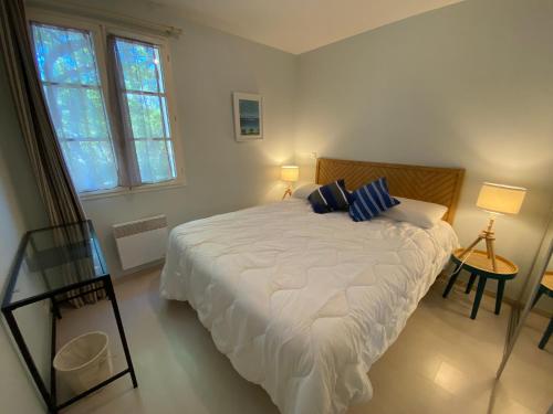 une chambre avec un grand lit blanc avec des oreillers bleus dans l'établissement Appartement T2 verdoyant avec parking privatif - FR-1-374-238, à Arcachon