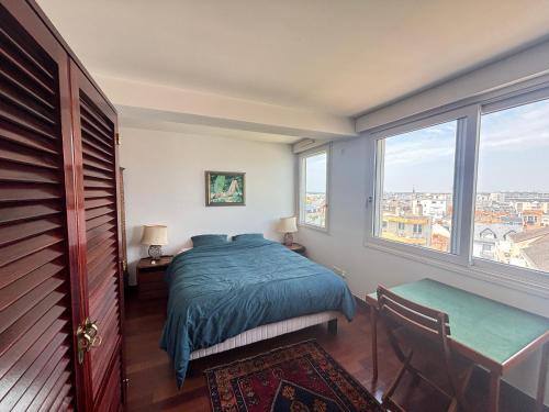 une chambre avec un lit, une table et des fenêtres dans l'établissement Appartement avec terrasse face plage, 4 pers - FR-1-197-629, à Les Sables-dʼOlonne