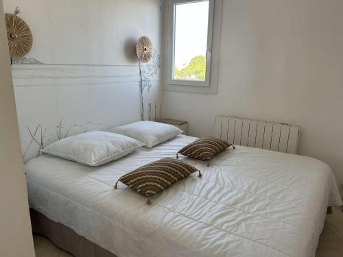 - un lit blanc avec deux oreillers et une fenêtre dans l'établissement Appartement 2 pièces, terrasse vue port, parking privé, clim, animaux admis - FR-1-250-313, au Grau-du-Roi