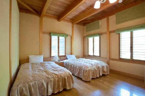 two beds in a room with windows and wooden floors at Izumigo Takayama Dog Paradise Hotel in Takayama