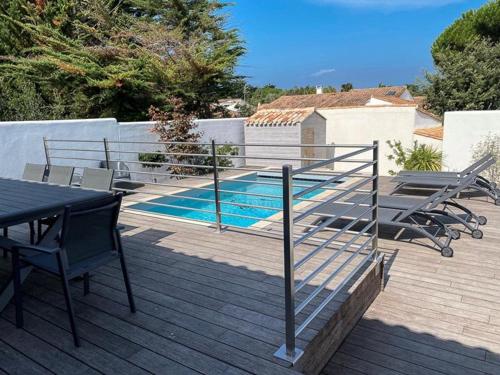 une terrasse avec une table et des chaises ainsi qu'une piscine dans l'établissement Villa 125m² avec piscine chauffée, 3 chambres, terrasse à La Flotte - FR-1-835-30, à La Flotte