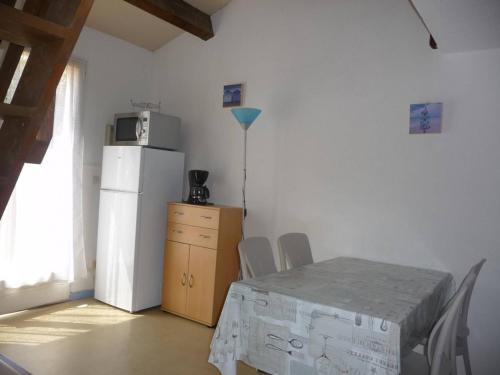 une salle à manger avec une table et un réfrigérateur dans l'établissement Maison climatisée avec terrasse et parking près de la plage - FR-1-782-77, au Barcarès