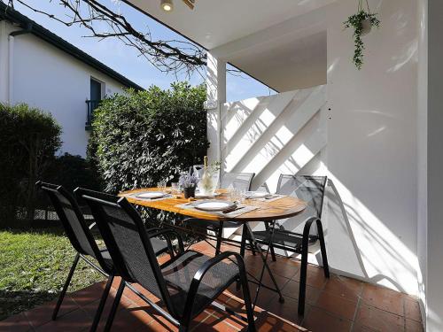 une table et des chaises en bois sur une terrasse dans l'établissement Appartement Hendaye avec piscine et parking - FR-1-2-443, à Hendaye