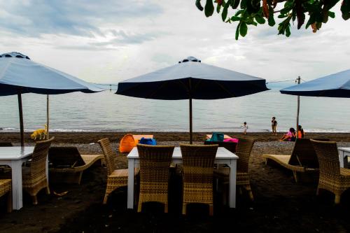 a table and chairs with umbrellas on the beach at Amed Sunset Beach in Amed