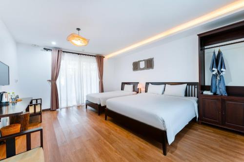 a hotel room with two beds and a desk at Ancient Garden Boutique Hoi An in Hoi An