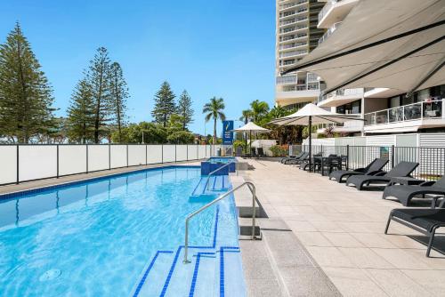 a swimming pool with chairs and a building at South Pacific Plaza - Official in Gold Coast
