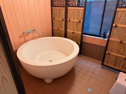 baño con bañera grande y ventana en 熱海網代くす亭, en Atami