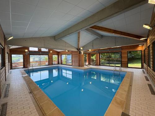 une piscine intérieure avec une grande pièce dotée de fenêtres dans l'établissement Chalet 6 pièces à Combloux avec cheminée et parking - FR-1-560-21, à Combloux