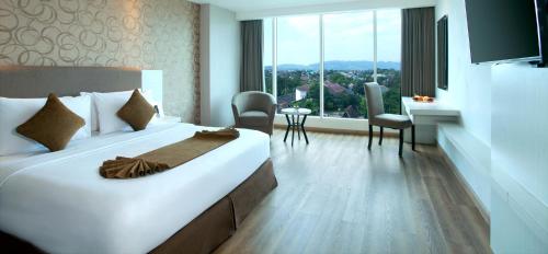 a hotel room with a large white bed and a table at Platinum Adisucipto Hotel & Conference Center in Yogyakarta