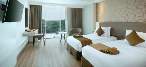 a hotel room with two beds and a television at Platinum Adisucipto Hotel & Conference Center in Yogyakarta
