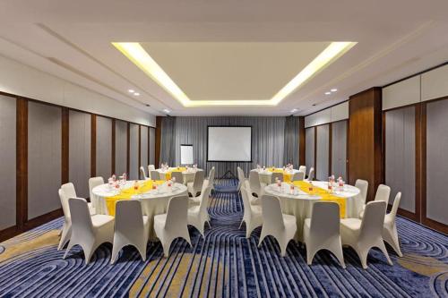 a conference room with tables and chairs and a screen at Kampi Hotel Tunjungan - Surabaya in Surabaya